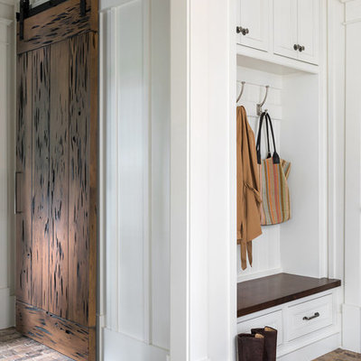 Mid-sized farmhouse brick floor and brown floor mudroom photo in Atlanta with white walls