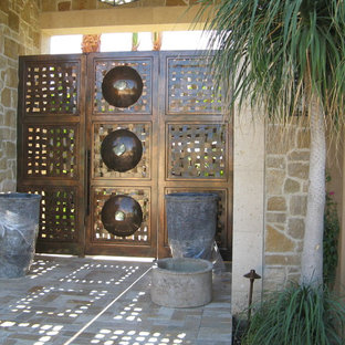 Exemple d'une grand porte d'entrée méditerranéenne avec un mur noir, béton au sol, une porte pivot et une porte métallisée.