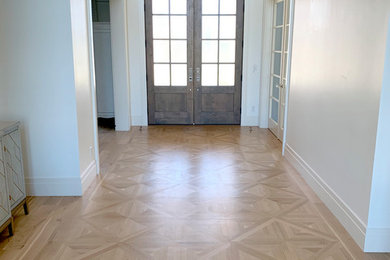 Ejemplo de distribuidor de estilo americano con paredes blancas, suelo de madera clara y puerta doble
