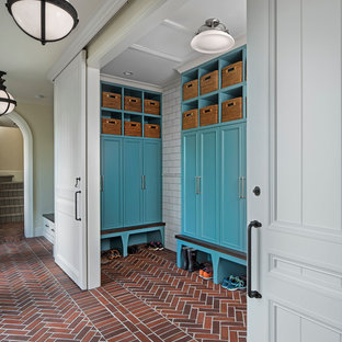 Example of a large classic brick floor and red floor mudroom design in Detroit with beige walls