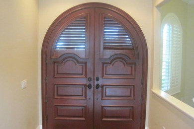 Mid-sized tuscan medium tone wood floor and brown floor entryway photo in Miami with beige walls and a dark wood front door