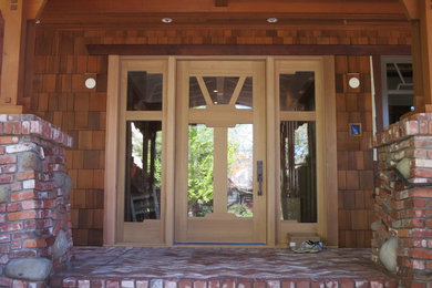 Idee per un'ampia porta d'ingresso american style con pavimento in mattoni, una porta singola e una porta in legno chiaro