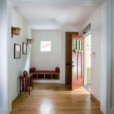 Example of a mid-sized arts and crafts medium tone wood floor and brown floor entryway design in Atlanta with a dark wood front door and white walls