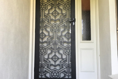 ゴールドコーストにある低価格の中くらいなミッドセンチュリースタイルのおしゃれな玄関ドア (黒いドア) の写真