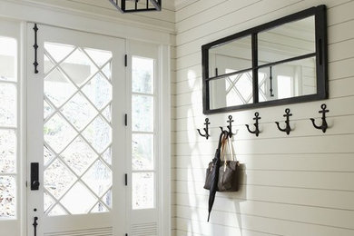 Example of a mid-sized beach style medium tone wood floor entryway design in Toronto with white walls and a glass front door