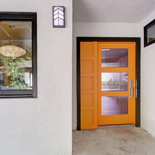 Esempio di una porta d'ingresso minimalista con pareti bianche, pavimento in cemento, una porta singola e una porta arancione