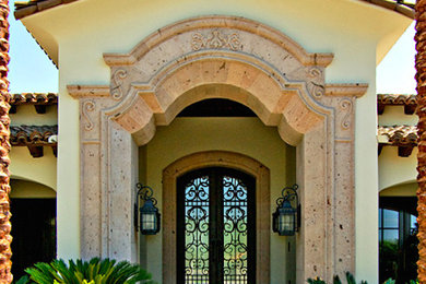 Modelo de puerta principal mediterránea grande con paredes beige, puerta doble y puerta metalizada