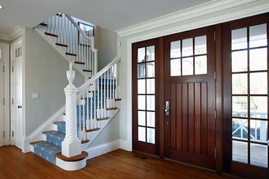 This is an example of a large hallway in New York with grey walls, medium hardwood flooring, a single front door and a dark wood front door.