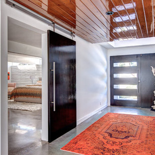 Imagen de hall actual, grande, con paredes blancas, suelo de cemento, puerta simple, puerta de vidrio y suelo gris