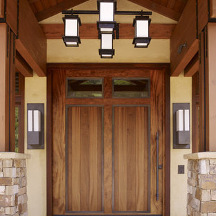 Modelo de puerta principal contemporánea con puerta de madera en tonos medios, paredes beige, suelo de piedra caliza, puerta pivotante y suelo beige