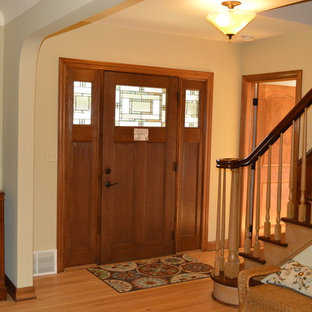 Ispirazione per una porta d'ingresso stile americano di medie dimensioni con pareti beige, pavimento in legno massello medio, una porta singola e una porta in legno scuro