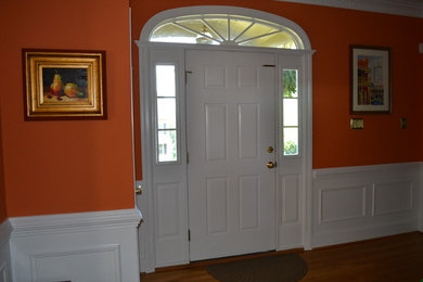 Foto de distribuidor clásico renovado pequeño con parades naranjas, suelo de madera clara, puerta simple y puerta blanca