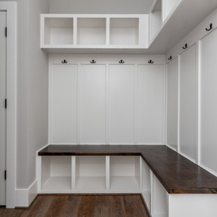 Exemple d'une entrée craftsman avec un vestiaire, un mur beige, un sol en bois brun et boiseries.