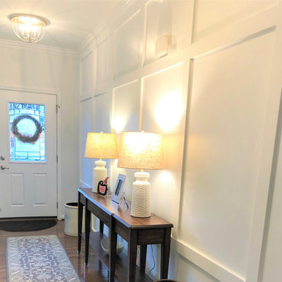 Example of a mid-sized transitional medium tone wood floor and wainscoting foyer design in Baltimore with white walls
