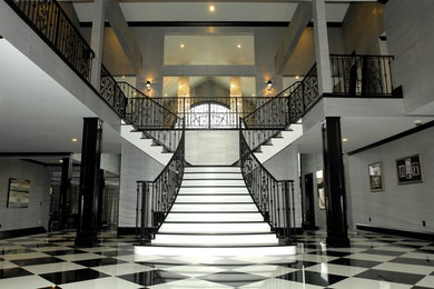 This is an example of a large contemporary foyer in New York with grey walls, granite flooring and a double front door.