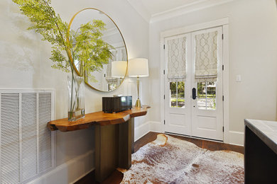 他の地域にある高級な中くらいなエクレクティックスタイルのおしゃれな玄関ロビー (白い壁、濃色無垢フローリング、白いドア、茶色い床) の写真