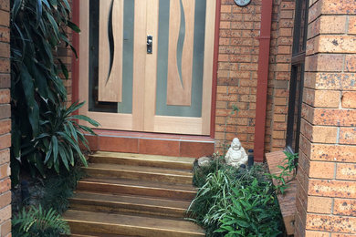 Inspiration for a small contemporary front door in Brisbane with brown walls, ceramic flooring, a double front door, a medium wood front door and brown floors.