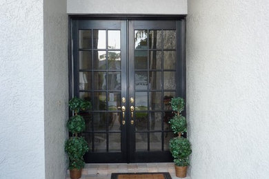This is an example of a traditional front door in Tampa with white walls, a double front door and a black front door.
