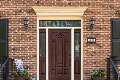 Example of a mid-sized classic brick floor entryway design in Raleigh with white walls and a brown front door