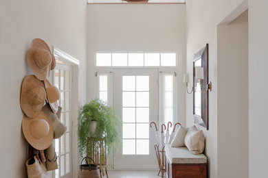 Cette photo montre une grande entrée avec un mur blanc, un sol en carrelage de céramique, une porte simple, une porte blanche et un couloir.