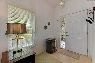 マイアミにある低価格の小さなビーチスタイルのおしゃれな玄関ロビー (白い壁、磁器タイルの床、白いドア、ベージュの床) の写真