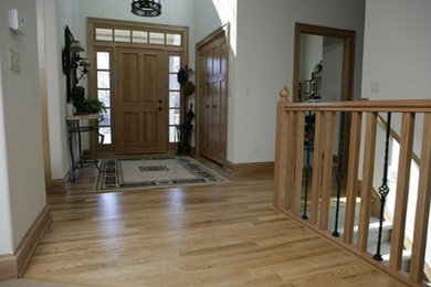 Modelo de distribuidor tradicional de tamaño medio con paredes blancas, suelo de madera clara, puerta simple, puerta de madera clara y suelo beige