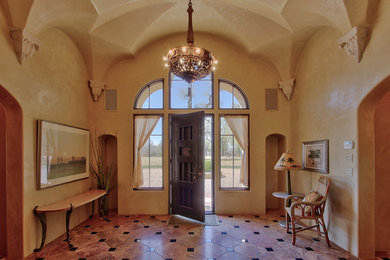 アルバカーキにあるお手頃価格の広いエクレクティックスタイルのおしゃれな玄関ロビー (ベージュの壁、磁器タイルの床、濃色木目調のドア、ベージュの床) の写真