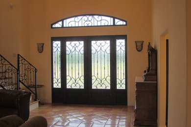 Terra-cotta tile entryway photo in Houston with beige walls and a glass front door