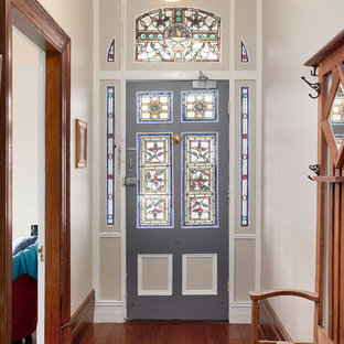 This is an example of a traditional front door in Sydney with beige walls, medium hardwood floors, a single front door, a gray front door and brown floor.