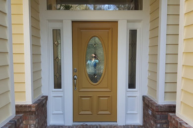 Ejemplo de puerta principal tradicional de tamaño medio con paredes amarillas, suelo de ladrillo, puerta simple, puerta amarilla y suelo rojo