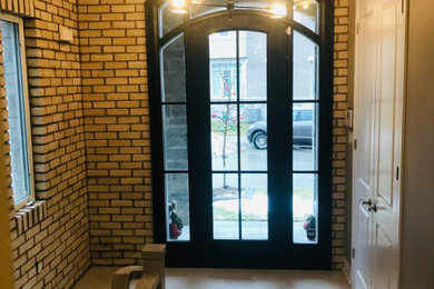 トロントにあるトラディショナルスタイルのおしゃれな玄関ドア (マルチカラーの壁、黒いドア、レンガ壁) の写真