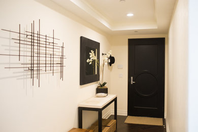Immagine di un piccolo corridoio moderno con pareti bianche, parquet scuro, una porta singola e una porta nera