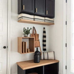 Immagine di un piccolo ingresso con anticamera minimalista con pareti bianche, parquet chiaro, una porta scorrevole e una porta nera