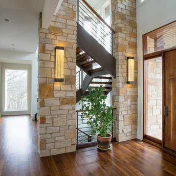 Foyer Featuring Stone Columns and Floating Open Tread Walnut Staircase with Waln