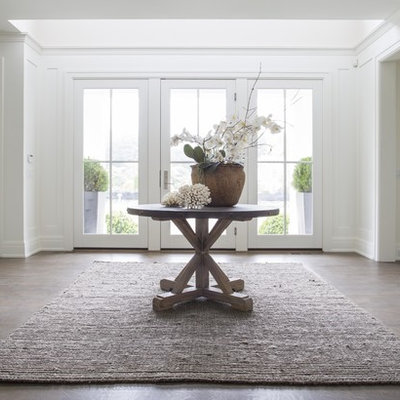 Example of a large transitional dark wood floor entryway design in New York with white walls and a glass front door