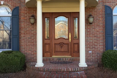 Ejemplo de puerta principal clásica grande con paredes rojas, suelo de ladrillo, puerta doble, puerta de madera oscura y suelo rojo