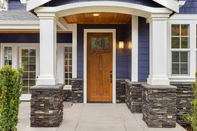 Modelo de puerta principal de estilo americano de tamaño medio con paredes púrpuras, suelo de cemento, puerta simple y puerta de madera en tonos medios