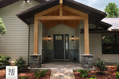 Example of a mid-sized mountain style concrete floor and red floor entryway design in Jacksonville with beige walls and a brown front door