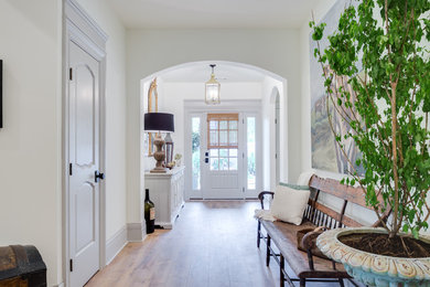 Large farmhouse foyer in Kansas City with white walls, medium hardwood flooring, a single front door, a white front door and feature lighting.