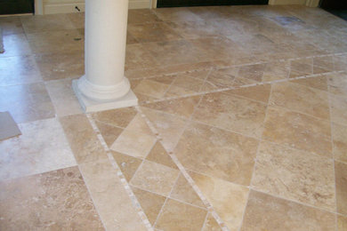 Example of a large travertine floor entryway design in Houston with beige walls and a dark wood front door