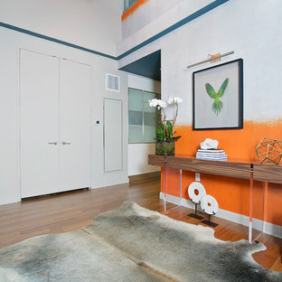 Exempel på en mellanstor modern foajé, med orange väggar, mellanmörkt trägolv, en dubbeldörr och en grå dörr