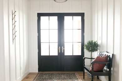 デンバーにある高級な中くらいなカントリー風のおしゃれな玄関ロビー (白い壁、無垢フローリング、黒いドア、茶色い床) の写真