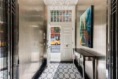Example of a classic marble floor entryway design in New York with a white front door