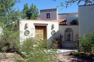 フェニックスにある高級な広いサンタフェスタイルのおしゃれな玄関ドア (白い壁、テラコッタタイルの床、木目調のドア、マルチカラーの床) の写真
