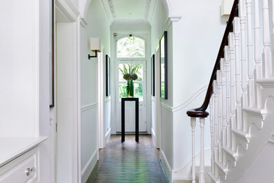 Ispirazione per un corridoio tradizionale con pareti bianche, parquet scuro, una porta singola, una porta bianca e pavimento marrone