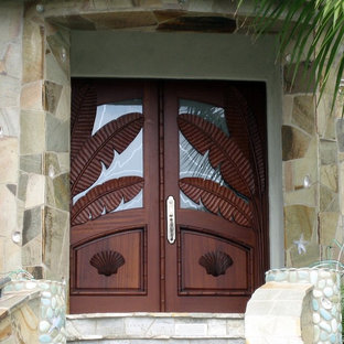 Esempio di un ingresso o corridoio tropicale con una porta a due ante e una porta in legno bruno