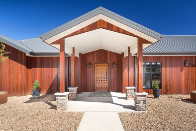 Große Rustikale Haustür mit brauner Wandfarbe, Betonboden, Einzeltür, heller Holzhaustür und grauem Boden in Sonstige