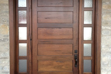 Cette image montre une grande porte d'entrée minimaliste avec une porte simple et une porte en bois brun.