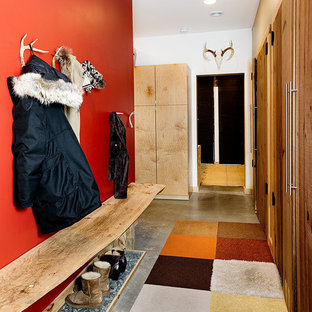 Immagine di un grande ingresso con anticamera stile rurale con pareti rosse, pavimento in cemento, pavimento grigio, una porta singola e una porta bianca