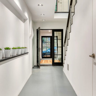 Moderner Eingang mit Korridor, weißer Wandfarbe, Betonboden, Einzeltür und schwarzer Tür in New York